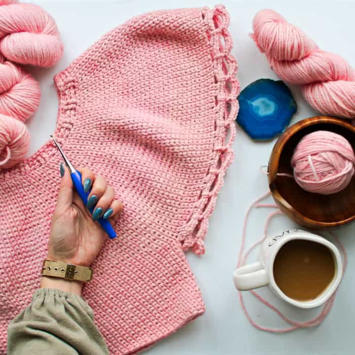 Furls Blue Odyssey Crochet Hook in a crocheter's hand on a pink sweater