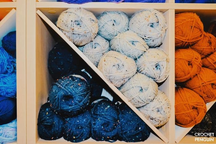 DIfferent colored heathered yarns on a wooden shelf. 