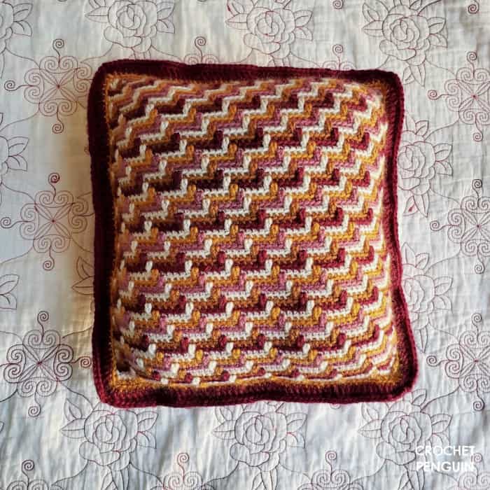 Apache Tears Stitch Mosaic crochet pillow by Jodie Morgan
The stitch looks like steps and colors are yellow, pink, white and plum. Background is a white quilt with machine stitched red roses.