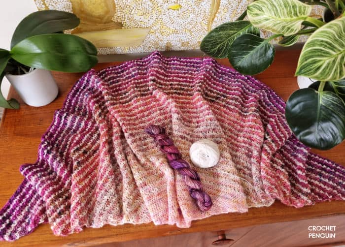 History Of Crochet - crocheted shawl in pinks, purples and white on a wooden table
