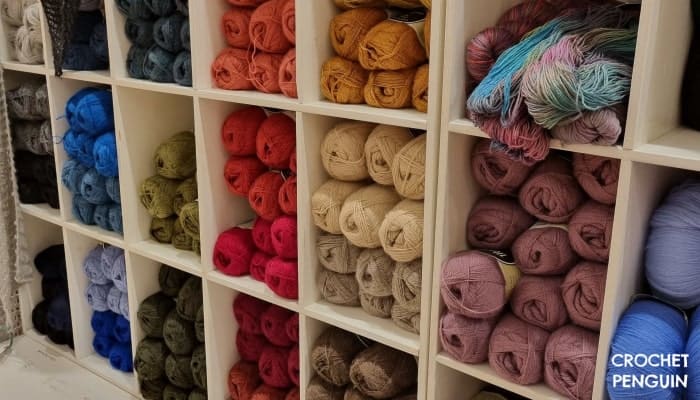 skeins of different colored yarns in white wall shelving - blues, reds, olive, puple, creams and greys
